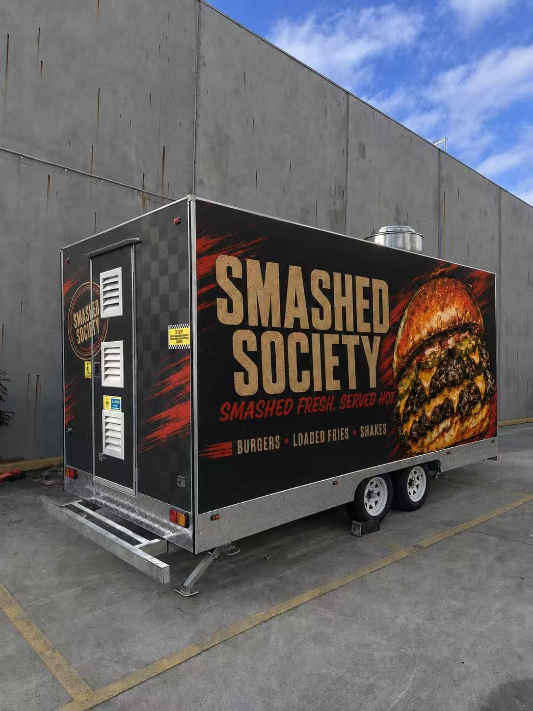 Rear-side angle of the Smashed Society wrapped food trailer